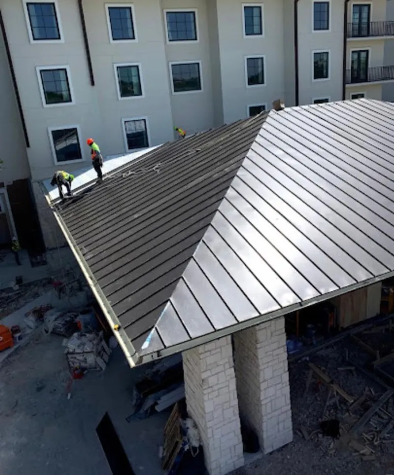 Crew installing standing seam metal roof panels on a commercial project in Matthews